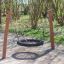 Altalena da parco giochi BNS Single Swing Robinia 2 Posts in legno con seduta nera in gomma in un parco.