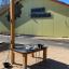 Tavolo attività esterno Sand & Water Play Nature per bambini davanti a un edificio scolastico.