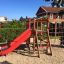 Climbing Kiosk (Wide Slide) con scivolo rosso in un parco giochi.