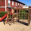 Attrezzatura da gioco Climbing Kiosk (Wide Slide) in un'area giochi sabbiosa con una struttura in legno, arrampicata con corde n
