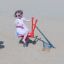 Bambino che gioca su un'attrezzatura da parco giochi rossa Excavator nella sabbiera