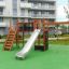 Attrezzatura da parco giochi Spiderman con scivolo, rete da arrampicata e scala in un cortile residenziale.