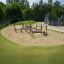 Parco giochi per bambini con strutture da arrampicata in legno in una sabbiera.