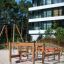 Course struttura da arrampicata per parco giochi in legno su terreno sabbioso vicino a un edificio residenziale