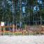 Course struttura da arrampicata e bilanciamento in legno per parco giochi in area sabbiosa con sfondo boschivo