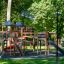 Grande struttura in legno per parco giochi con più scivoli e aree per arrampicarsi in un parco