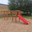 Activity Center with Slide su un parco giochi sabbioso con elementi da arrampicata e scivolo rosso