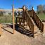 Moderna casetta da gioco in legno con rete da arrampicata e scale nel parco giochi
