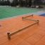 Balance attrezzatura da parco giochi con travi su un tappeto arancione con un campo verde sullo sfondo.