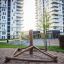 Struttura da arrampicata in legno Atakama in un parco giochi davanti ad alti edifici residenziali.