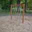 V-shape Net wooden playhouse in un'area giochi sabbiosa circondata da alberi.