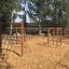 V-shape Net wooden playhouse in un parco giochi con reti da arrampicata e pavimentazione in cippato di legno.