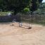 Single Seesaw in un'area giochi sabbiosa circondata da una recinzione in legno.
