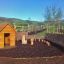 Nature Playhouse in un ambiente naturale all'aperto con strutture da gioco in legno e recinzione in vimini.