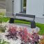 Moderno Sydney Bench in un giardino paesaggistico con fiori e vegetazione.