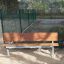 HPL Bench in un parco con gambe in metallo e seduta e schienale in legno.