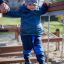 Un bambino che attraversa l'attrezzatura da gioco Chain Bridge con il supporto di un adulto.