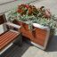 Oxford Flowerpot realizzato in legno e metallo, riempito con fiori rossi e piante verdi, posizionato accanto a un 