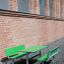 Table & Bench HPL verde posizionato contro un muro di mattoni all'aperto.