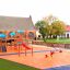 Attrezzatura da parco giochi Somersault Double in un'area giochi colorata con altalene a molla rosse e gialle e