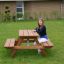 Larchwood Table & Bench for Kids con una ragazza seduta sulla panchina in un ambiente da giardino