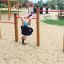 Bambino appeso a testa in giù sulla Somersault Triple in un parco giochi.