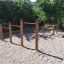 Parco giochi all'aperto con attrezzatura da arrampicata in legno Somersault Triple e barre rosse.