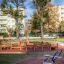 Attrezzatura fitness da esterno in un parco con alberi e palazzi sullo sfondo.