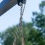 Attacco a catena di Safety Seat Single Swing al telaio con alberi verdi sullo sfondo