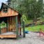 Struttura da gioco in legno per esterni Nill's Playhouse per bambini in un contesto di parco.