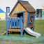 Casetta da gioco in legno per bambini Olle's Playhouse con una scala blu e uno scivolo.