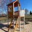 Casetta da gioco in legno con scala e scivolo in un parco giochi all'aperto